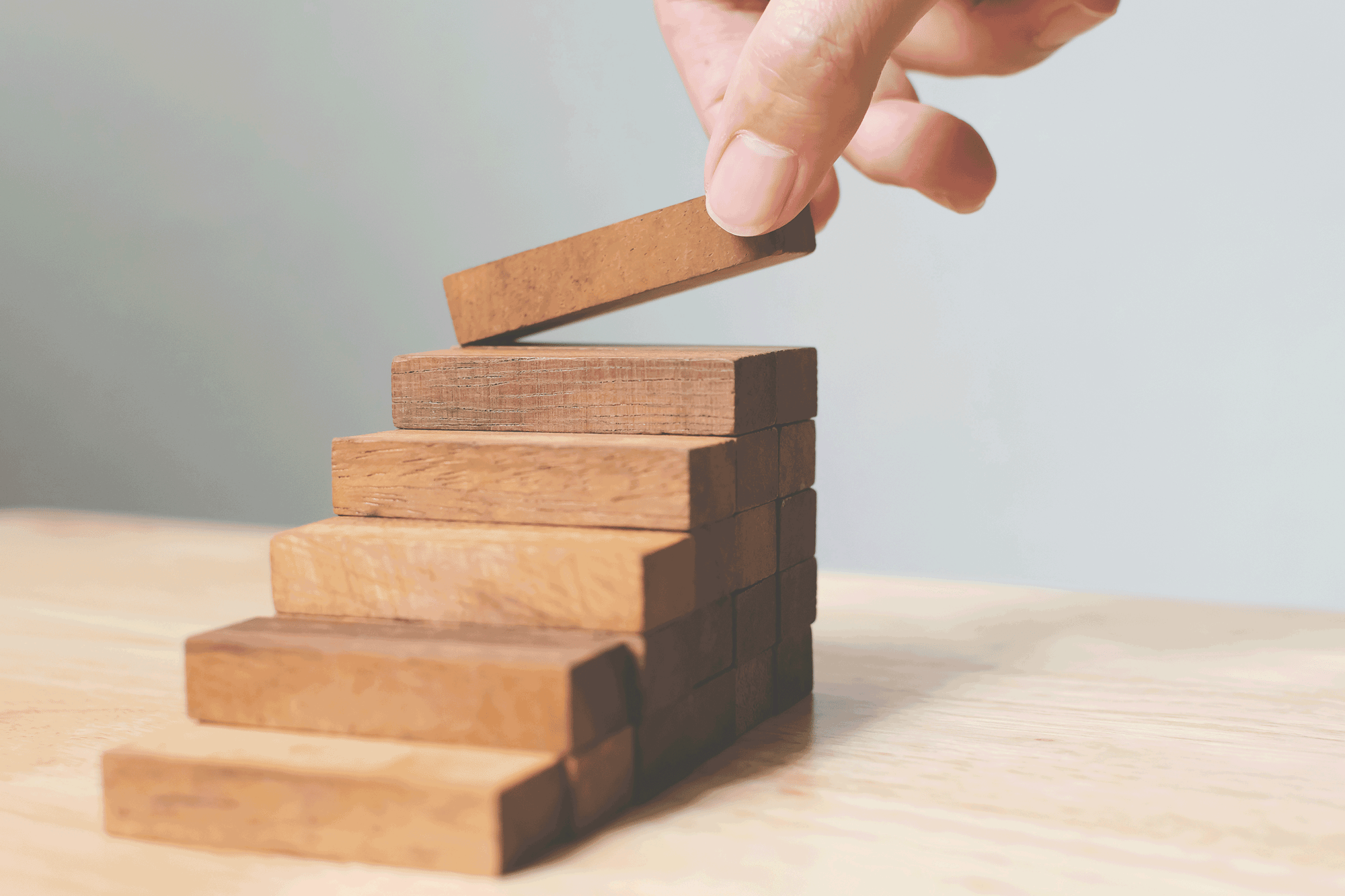 Hand baut aus Holzklötzen eine Treppe.